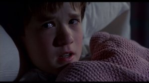 Scene in The Sixth Sense. Haley Joel Osment utters his famous "I see dead people" speech. He's in a hospital bed with a pink, woolen blanket.